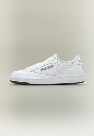 Baskets basses blanches Reebok avec lacets, embout perforé et logo Union Jack sur le côté avec bord de semelle sombre.