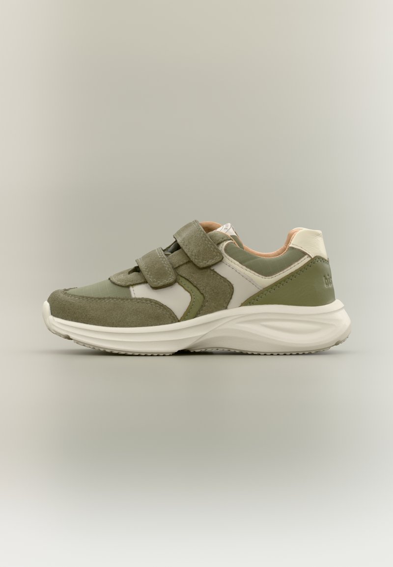 Χαμηλό αθλητικό παπούτσι σε ελιά πράσινο, μπεζ και λευκό με δύο ρυθμιζόμενους ιμάντες Velcro και παχύ λευκό πέλμα.