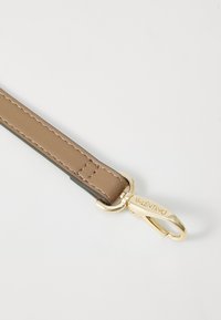 Sangle en cuir beige avec coutures contrastées et un clip en métal doré. Présente un logo embossé sur la quincaillerie et une texture lisse.