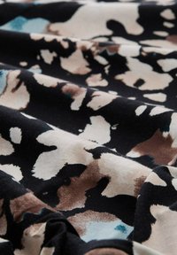 Tessuto con una texture stropicciata che presenta un motivo di stampa animale astratto nei colori nero, beige, marrone e con accenni di blu.
