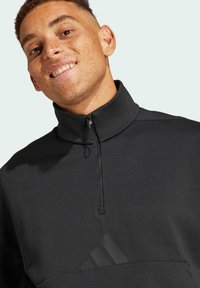 Svart kvartslång dragkedja sweatshirt med hög krage, med en slät yta och en subtil logodetalj framtill.