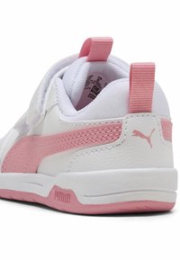 Hvite syntetiske sneakers med rosa stripe og detaljer, teksturert materiale, polstret krage og en løftestropp på hælen. PUMA-logo synlig.
