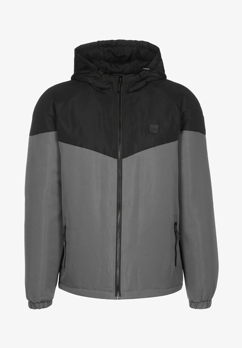 Veste d’hiver à capuche pour homme avec partie supérieure noire, partie inférieure et manches grises, fermeture éclair avant et poches latérales zippées.