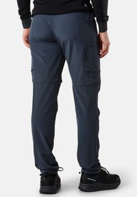 Navy blue cargo pants with reinforced knees, multiple side pockets, and a smooth texture, paired with black athletic shoes.