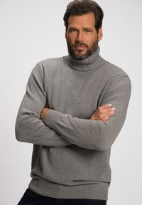 Grijze coltrui met geribbelde textuur, aansluitende manchetten en zoom. De stof lijkt zacht en gebreid, met een subtiel patroon en dikte.
