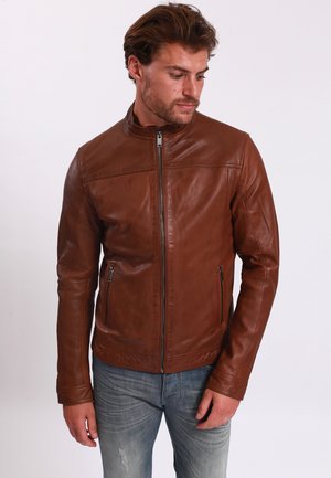 Chaqueta de cuero marrón con cuello alzado, cierre frontal con cremallera y dos bolsillos laterales con cremallera. Presenta una textura suave y un diseño ajustado.
