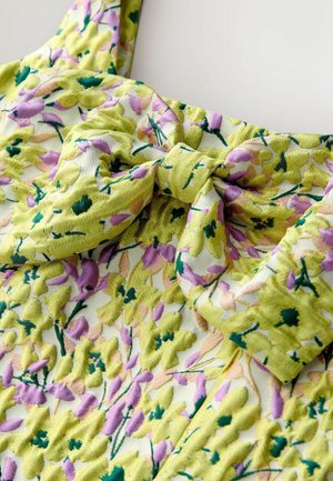 Floral dress with a yellow-green base, featuring a bow detail. The fabric has a soft texture with raised floral patterns in pink and green.