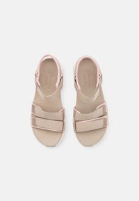 Sandalias de dedo en color beige con correas ajustables de Velcro y ribete rosa, que cuentan con plantillas Arch Fit acolchadas, vistas desde arriba sobre un fondo blanco.