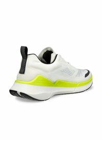 Scarpa da ginnastica bianca con parte superiore testurizzata, dettagli neri e suola gialla fluorescente. Presenta un'etichetta di trazione e un design flessibile per il massimo comfort.