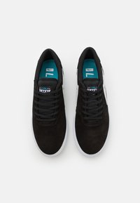 Black suede sneakers with a smooth texture, white rubber sole, and teal accents on the insole. Features black laces and logo detail.