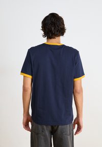 Marineblaues T-Shirt mit kurzen Ärmeln, gelbem geripptem Kragen und Ärmelsäumen, aus Baumwolle gefertigt, mit einem schlichten Design ohne sichtbare Logos.