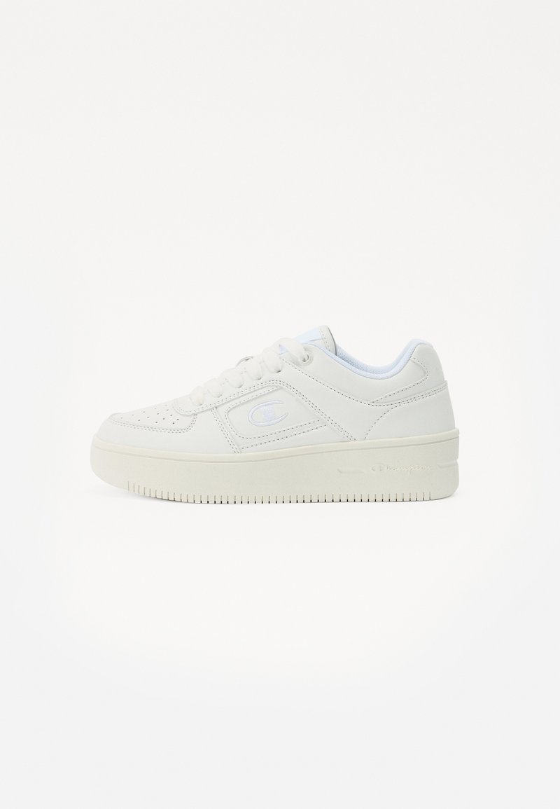 Balti sneakersai su lygiu odiniu viršumi, perforuota nosimi, paminkštintu apykakle ir storu guminėmis padais. Šone yra subtilus logotipas.