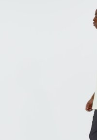 Light-colored shirt with a relaxed fit and short sleeves, paired with dark trousers. Minimalist design against a plain background.