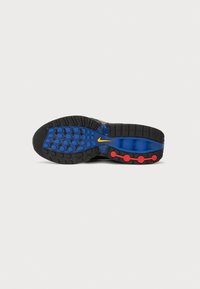 Semelle de basket noire avec une semelle bleue, des cercles rouges et un logo Nike swoosh jaune, sur fond blanc.