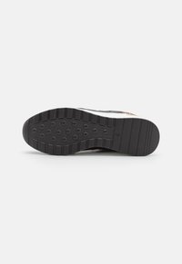 Black outsole with textured grip and hexagonal patterns. Features a raised, flat heel area and side grooves for flexibility.