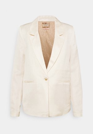 Kremowa damska marynarka z pojedynczym złotym guzikiem, klapami z wycięciami, dwoma przednimi kieszeniami oraz wzorzystą podszewką wewnętrzną.