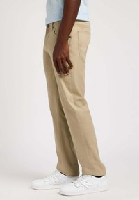 Beige broek van katoenmix, met een rechte pijpdesign, zijzakken en subtiele stiksels, gecombineerd met witte sneakers.