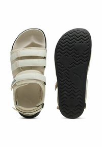 Hvide sandaler med tre justerbare stropper, gummiydersål med zigzag mønster, polstret indersål og et logo på siden.