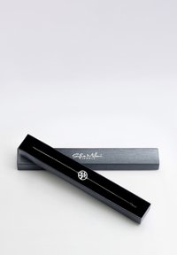 Silverarmband i en svart kartongask, med en cirkulär berlock med minimalistisk design och rhinestones.