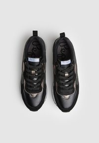 Černé sportovní boty kombinující kožené a síťované materiály, se šňůrkami, polstrovanou podrážkou a kovovými akcenty.