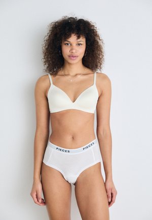 Cream bra with adjustable straps, smooth texture, and a V-shaped neckline; paired with white cotton briefs featuring a waistband labeled "PIECES."