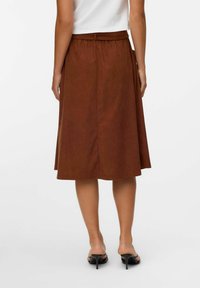 Jupe midi marron avec une texture lisse, ceinture à la taille et design plissé, présentant une couleur unie et un ourlet droit.