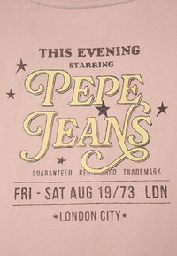 Světle růžové tričko s černou a žlutou typografií. Text zahrnuje "PEPE JEANS" se hvězdami a daty "PÁ - SO 19/73 LDN".