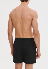 Czarne kąpielówki z elastycznym paskiem w talii, jedną kieszenią z tyłu i gładką teksturą. Dopasowane w standardowym kroju dla wygody.