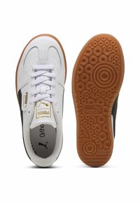 Białe i czarne sneakersy z gumową podeszwą, okrągłymi perforacjami oraz teksturowanym wzorem. Posiadają złote logo "Puma" z boku.