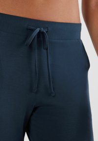 Granatowe dresy wykonane z miękkiego materiału, z elastycznym pasem i regulowanym sznurkiem. Posiadają boczne kieszenie oraz gładką fakturę.