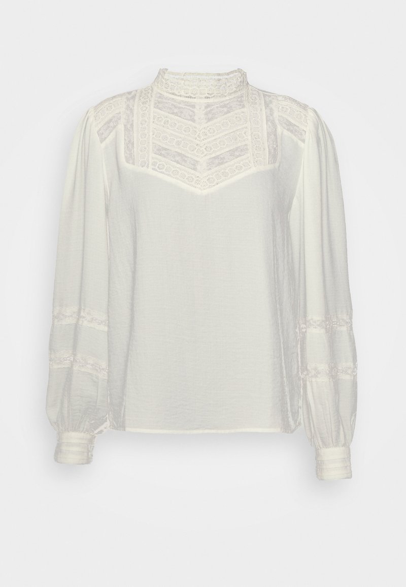 Blouse blanche à manches longues avec inserts en dentelle sur la poitrine, les épaules et les manches, dotée d’un col haut en dentelle et de poignets boutonnés.