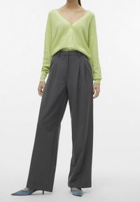 Cardigan de punto verde claro con escote en V y botones, combinado con pantalones de pierna ancha grises. Tacones puntiagudos azules claros completan el conjunto.