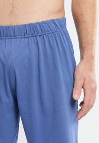 Pantalons de lounge en coton bleu avec une taille élastique et une texture lisse, présentant une coupe décontractée et sans motifs ni accents visibles.