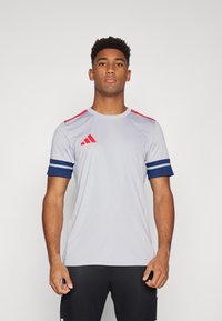 Gray athletic T-shirt with short sleeves, red accents on shoulders, and navy blue stripe detail on cuffs. Front displays three-stripe logo.