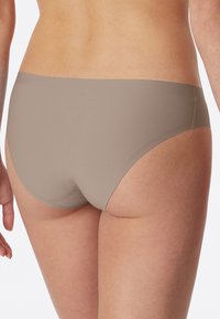 Beige hipster underwear with a smooth, seamless design and elastic waistband, showcasing a soft, matte texture.