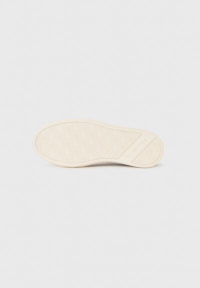 Beige kinga taldil on korduv ahel-linkide muster ja brändinimi "Filling Pieces" on reljeefselt tõstetud kanna lähedal.