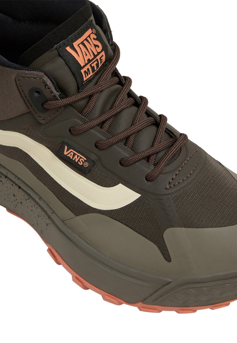 Sneaker brune Vans MTE avec une tige texturée, rayure latérale crème, semelle épaisse avec des accents orange et un design classique à lacets.