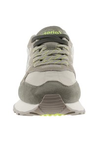 Sneaker grigie e beige realizzate con materiali in suede e mesh, caratterizzate da dettagli verdi sui lacci, linguetta imbottita e suola in gomma testurizzata.