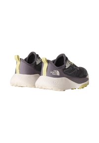 Scarpe da ginnastica sintetiche grigie con suola bianca testurizzata, accentuate da un tab del tallone giallo. Presentano un logo nero sul lato e pannelli in rete.