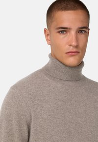 Pull en col roulé gris clair, fabriqué en tricot doux et texturé. Présente un col haut et une coupe ajustée, idéal pour le superposition.
