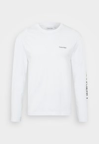 Weißes Langarmhemd von Calvin Klein mit Rundhalsausschnitt und kleinem "Calvin Klein"-Logo auf der linken Brust sowie großem Schriftzug auf dem rechten Ärmel.