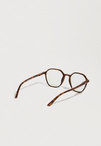 Kilpikonnakuosiset silmälasit, joissa kahdeksankulmainen kehys, läpinäkyvät linssit ja ohuet sarvet. Kuvioissa näkyy huomattavia ruskean ja meripihkan sävyjä.