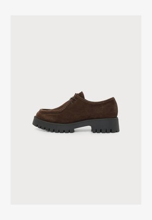 Dark brown suede lace-up shoe with thick black chunky sole, rounded toe, and low heel, shown from the side on a white background.