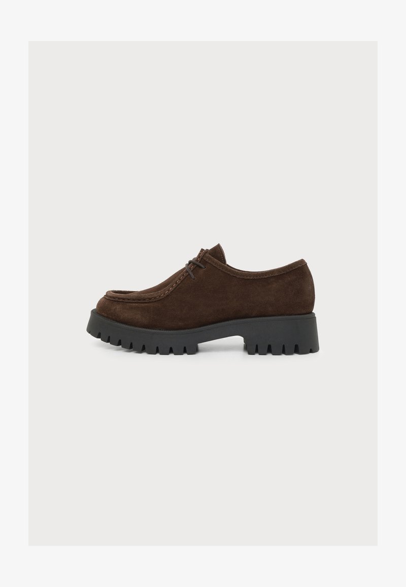 Chaussure à lacets en daim marron foncé avec une semelle épaisse noire et imposante, bout arrondi et talon bas, vue de côté sur fond blanc.