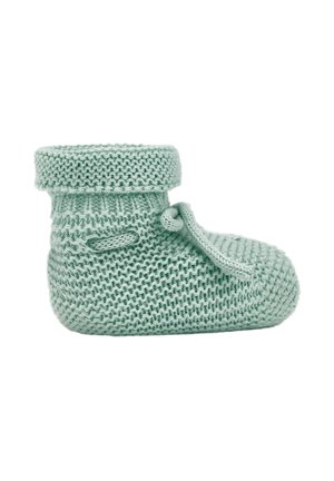 Chausson de bébé doux tricoté vert clair avec un revers et un nœud noué sur le côté, présenté sur fond blanc.