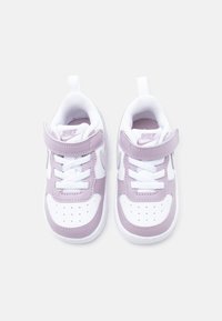 Beli in sivkini otroški čevlji Nike z gladkim sintetičnim zaključkom, vezalkami in zapiranjem na ježka, oblazinjenim ovratnikom ter perforiranimi detajli na prstih.