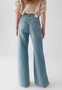Lichtblauwe wijde jeans met een hoge taille, gemaakt van denim, met achterzakken en een schone tailleband. Minimalistisch ontwerp, geen zichtbare hardware.