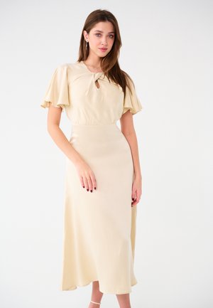 Abito midi beige con maniche corte a volants, dettaglio a chiave nel colletto, texture liscia e orlo svasato.