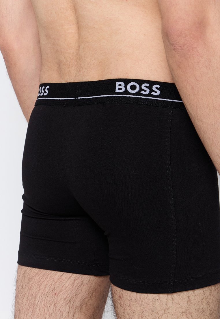 Homme portant un boxer noir avec le logo BOSS sur la ceinture, vu de dos au niveau de la taille jusqu'au milieu de la cuisse.