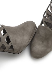 Graue Kunstwildleder-Stiefeletten mit offenem Gitterdesign, spitzen Zehen und einer glatten Textur. Minimalistischer Stil mit schwarzen Sohlenelementen.